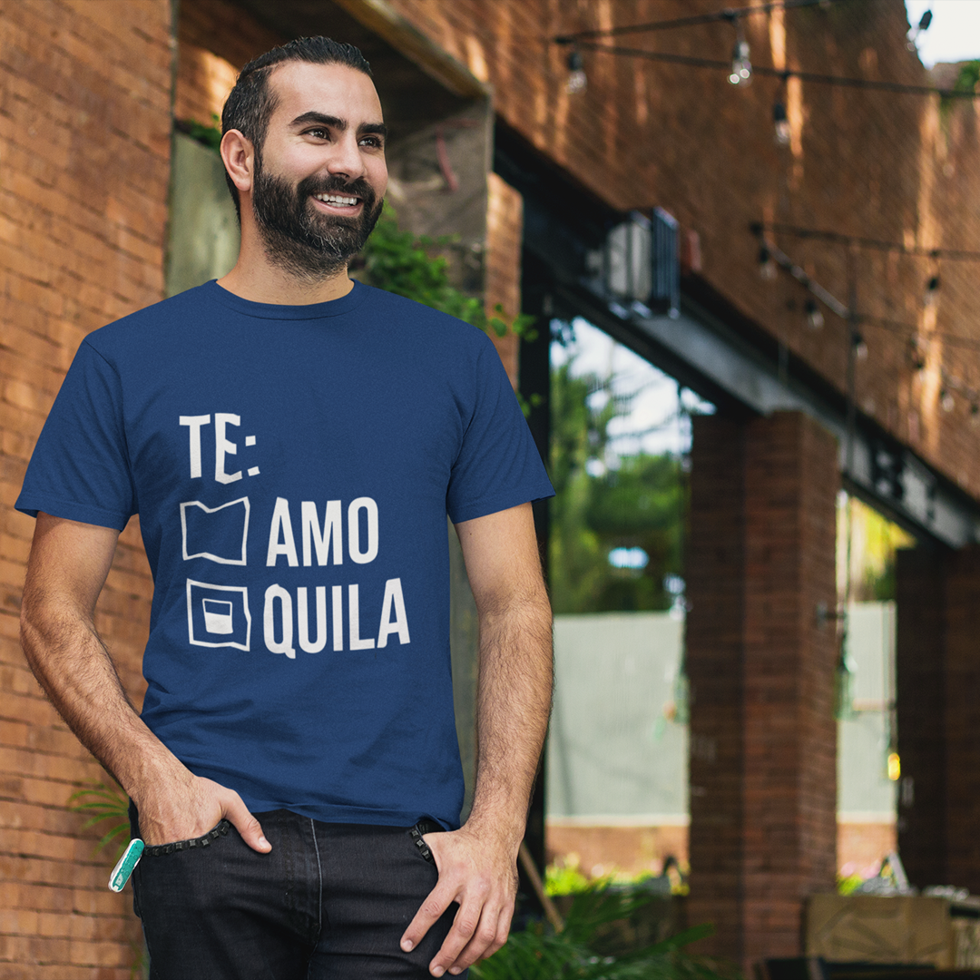 Man wearing a blue t-shirt with text standing outdoors near a brick wall.