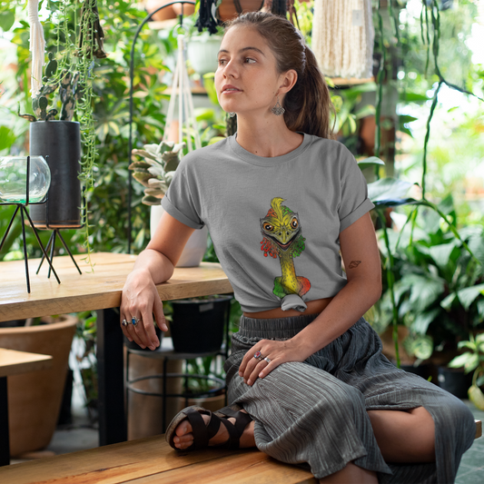 Woman sitting in a plant-filled room wearing a gray t-shirt with a colorful graphic design.