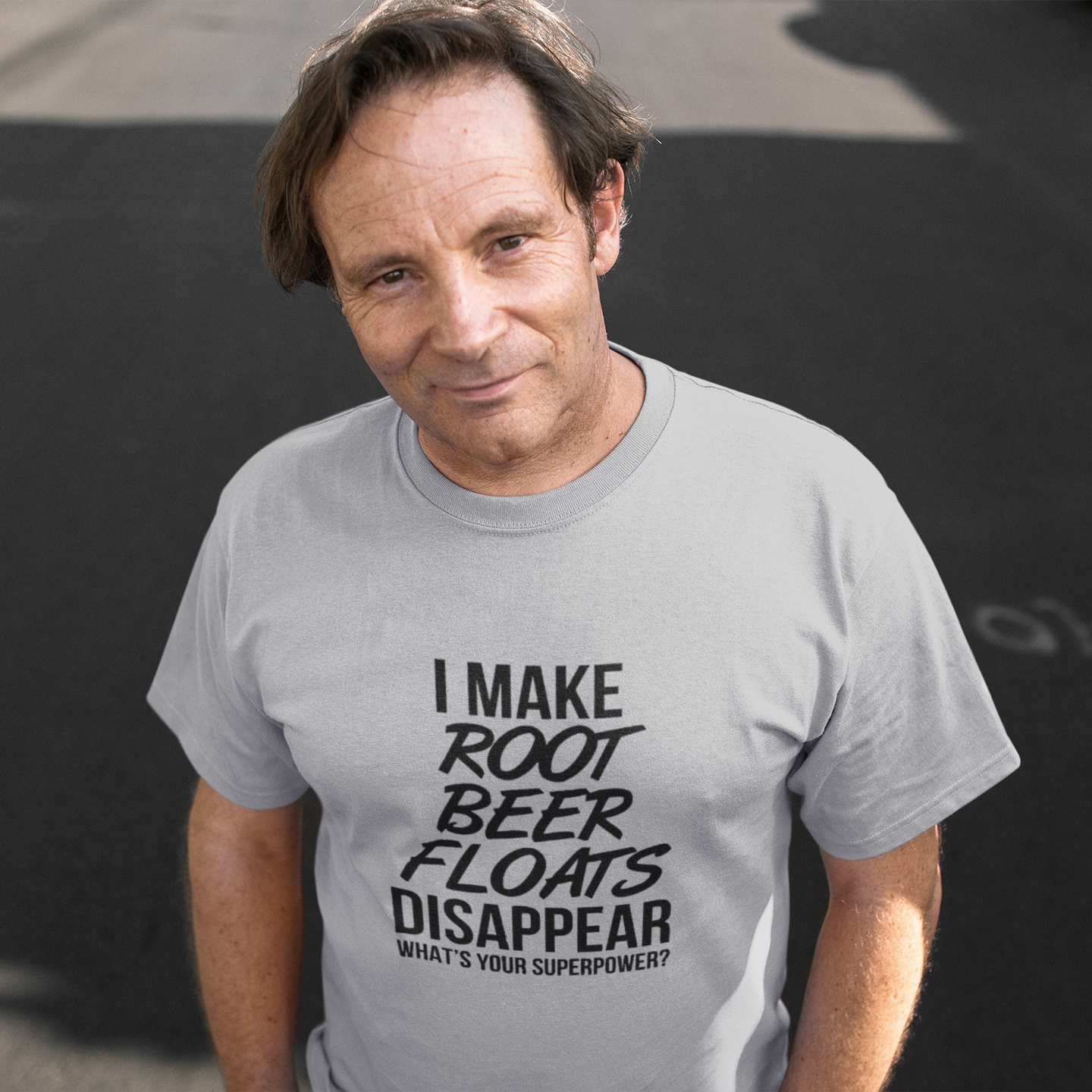 Man wearing a gray t-shirt with a humorous text design on a dark background