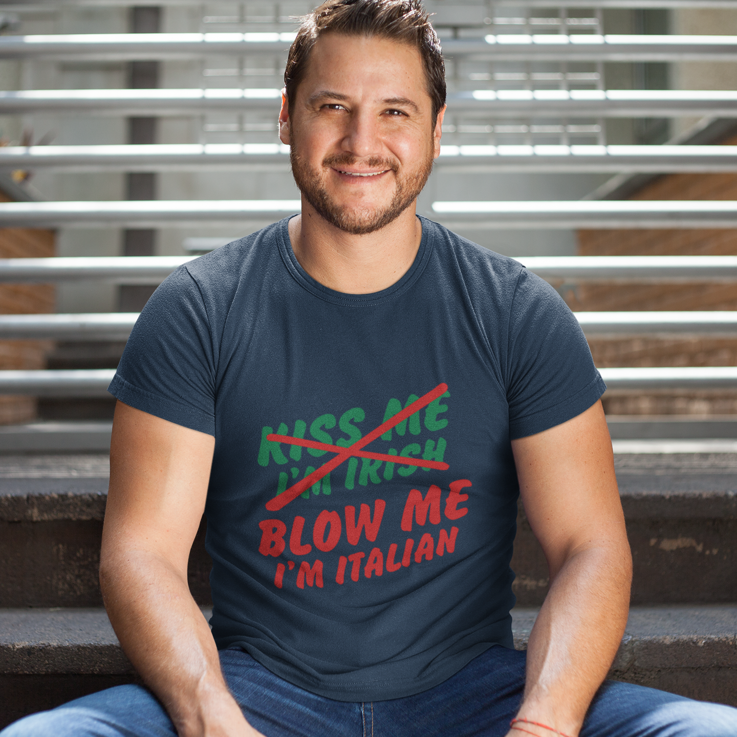 Man wearing a navy blue t-shirt with colorful text, sitting on steps.