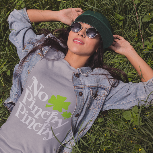 Woman lying on grass wearing a denim jacket and sunglasses, with a shirt that says 'No Pinchy Pinchy'.