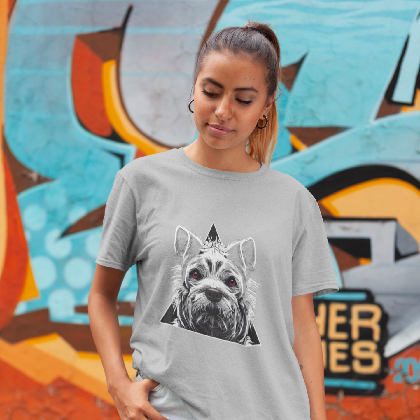 Woman wearing a gray t-shirt with a dog graphic in front of a colorful mural.