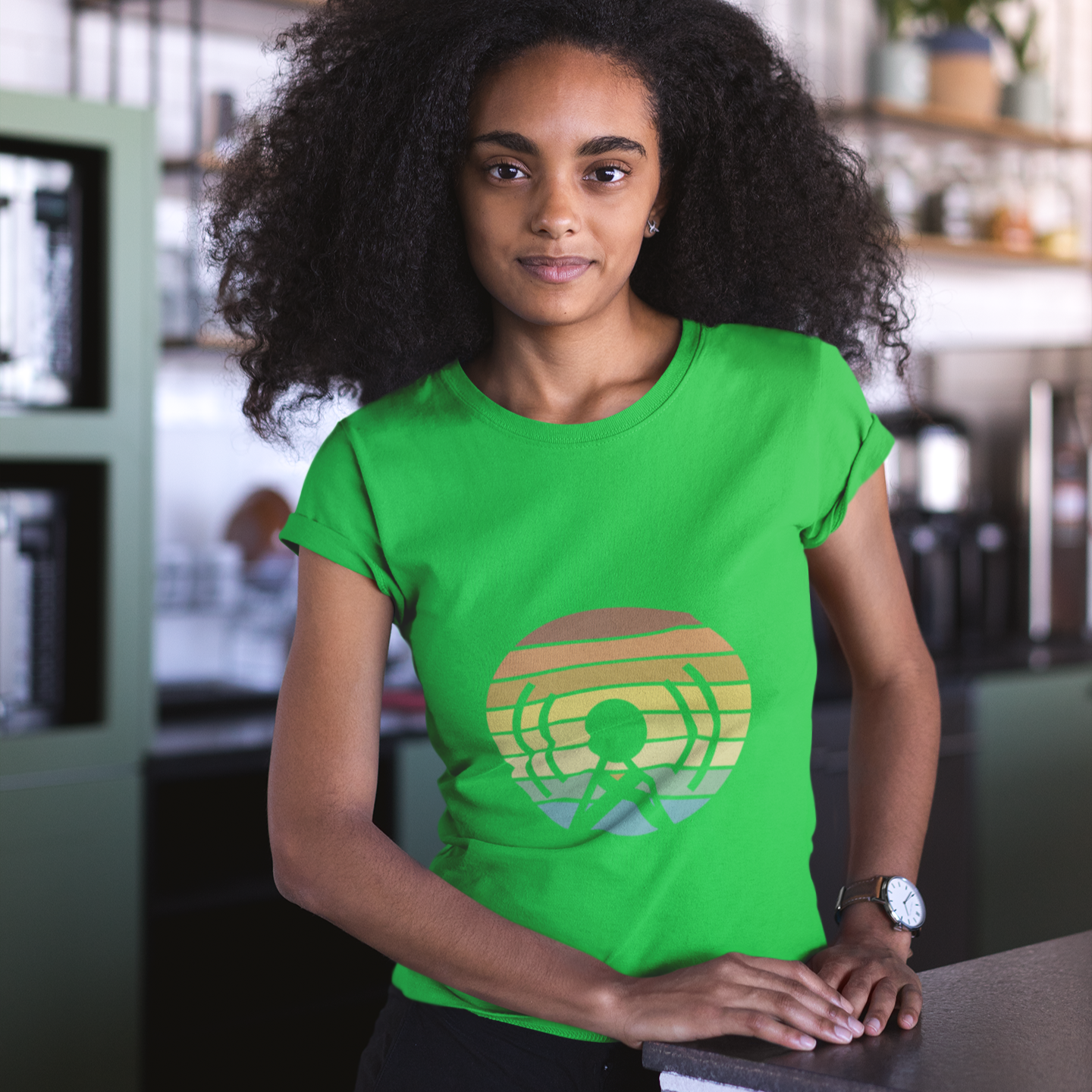 Person wearing a green t-shirt with a colorful logo in an indoor setting