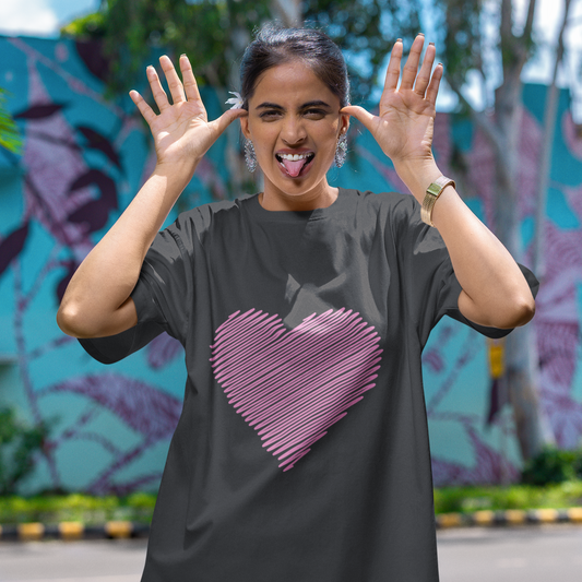 Woman wearing a black t-shirt with a pink heart design, standing outdoors with a colorful mural in the background.