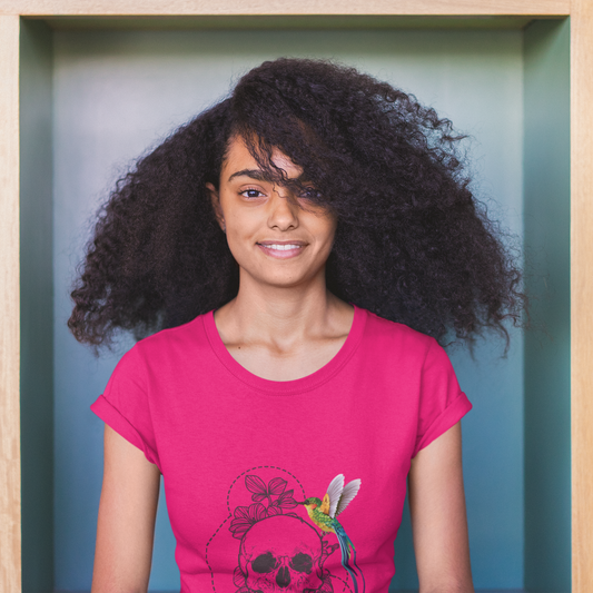 Person wearing a pink t-shirt with a colorful design, standing against a teal background.