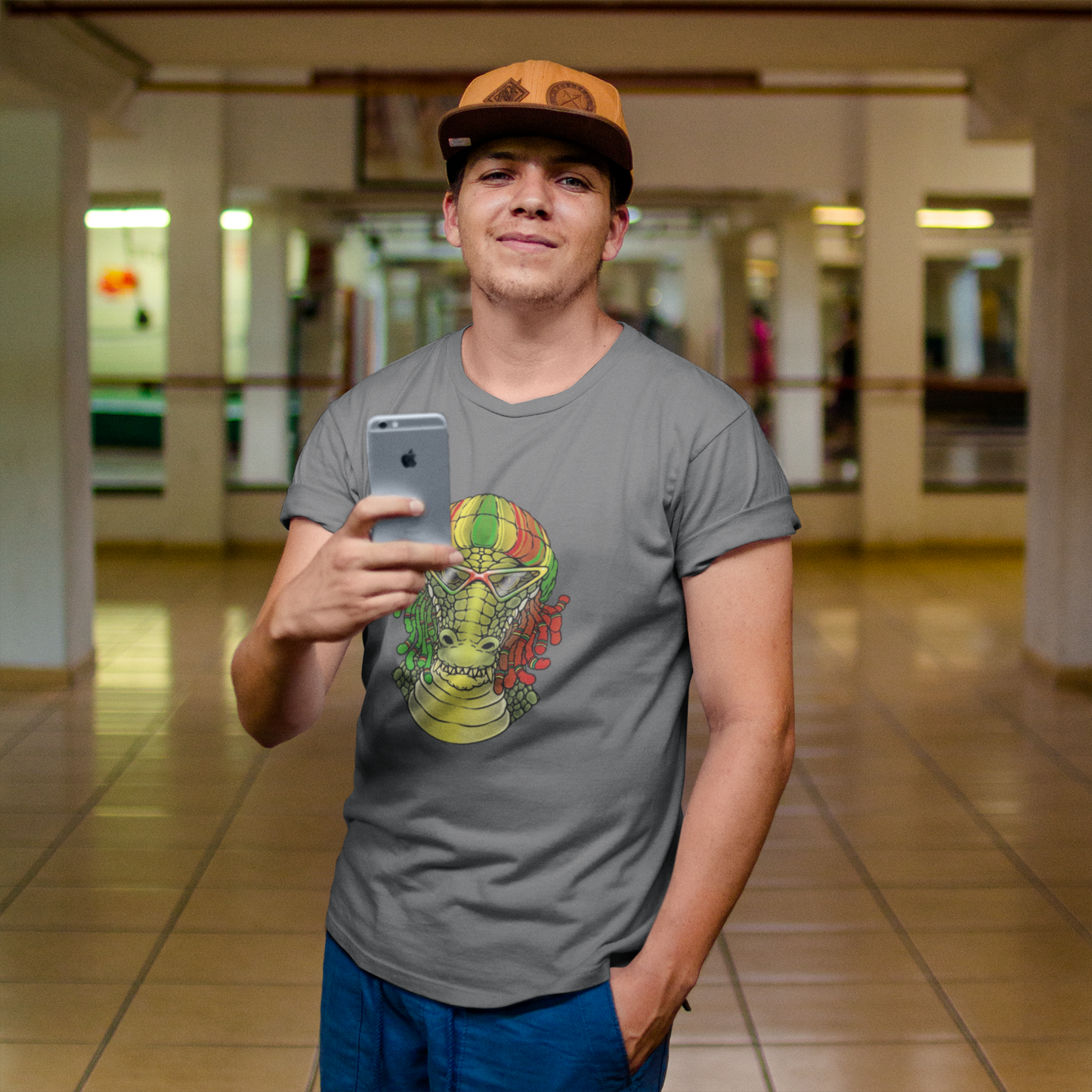 Person wearing a gray t-shirt with a colorful graphic design, holding a phone in an indoor setting.