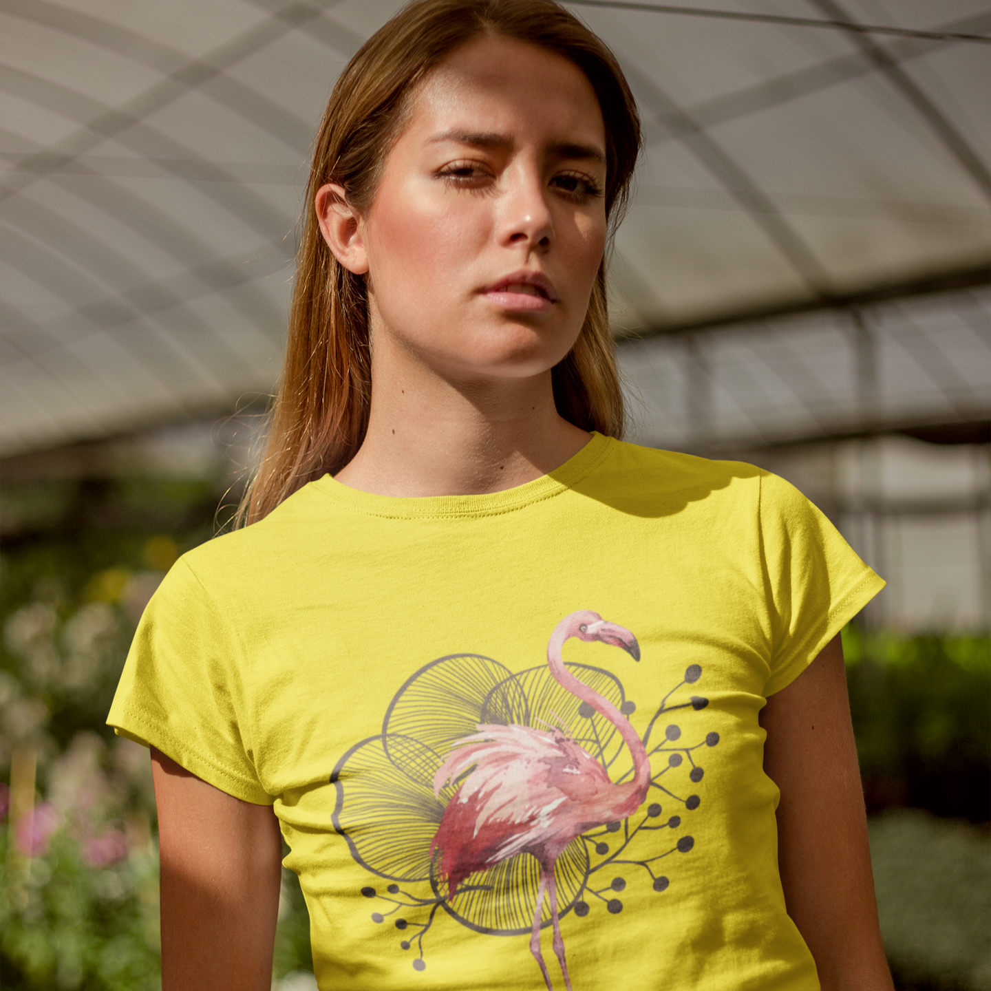 Woman wearing a bright yellow t-shirt with a flamingo design in an outdoor setting.