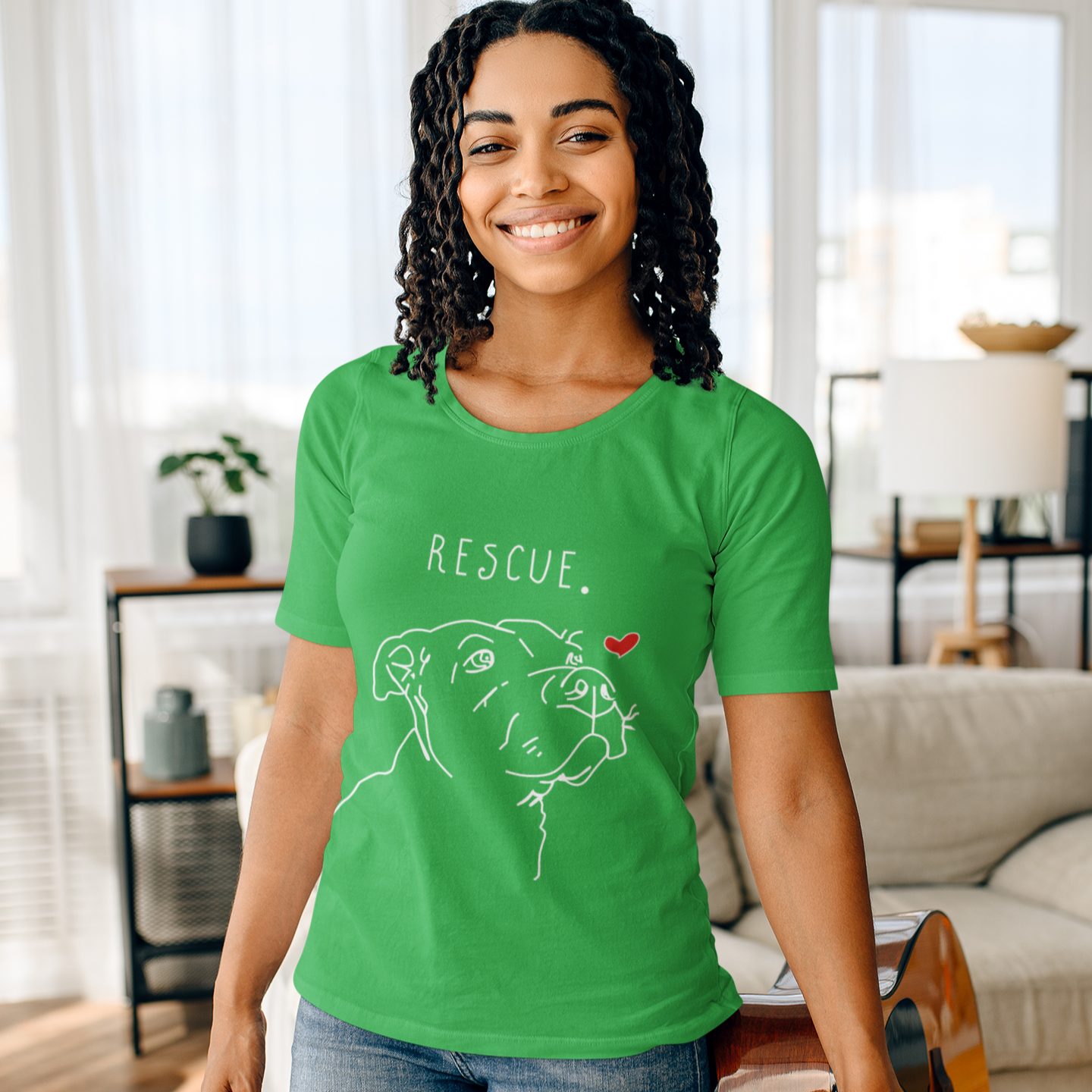 Woman wearing a green t-shirt with 'Rescue' and a dog illustration, holding a guitar in a living room.