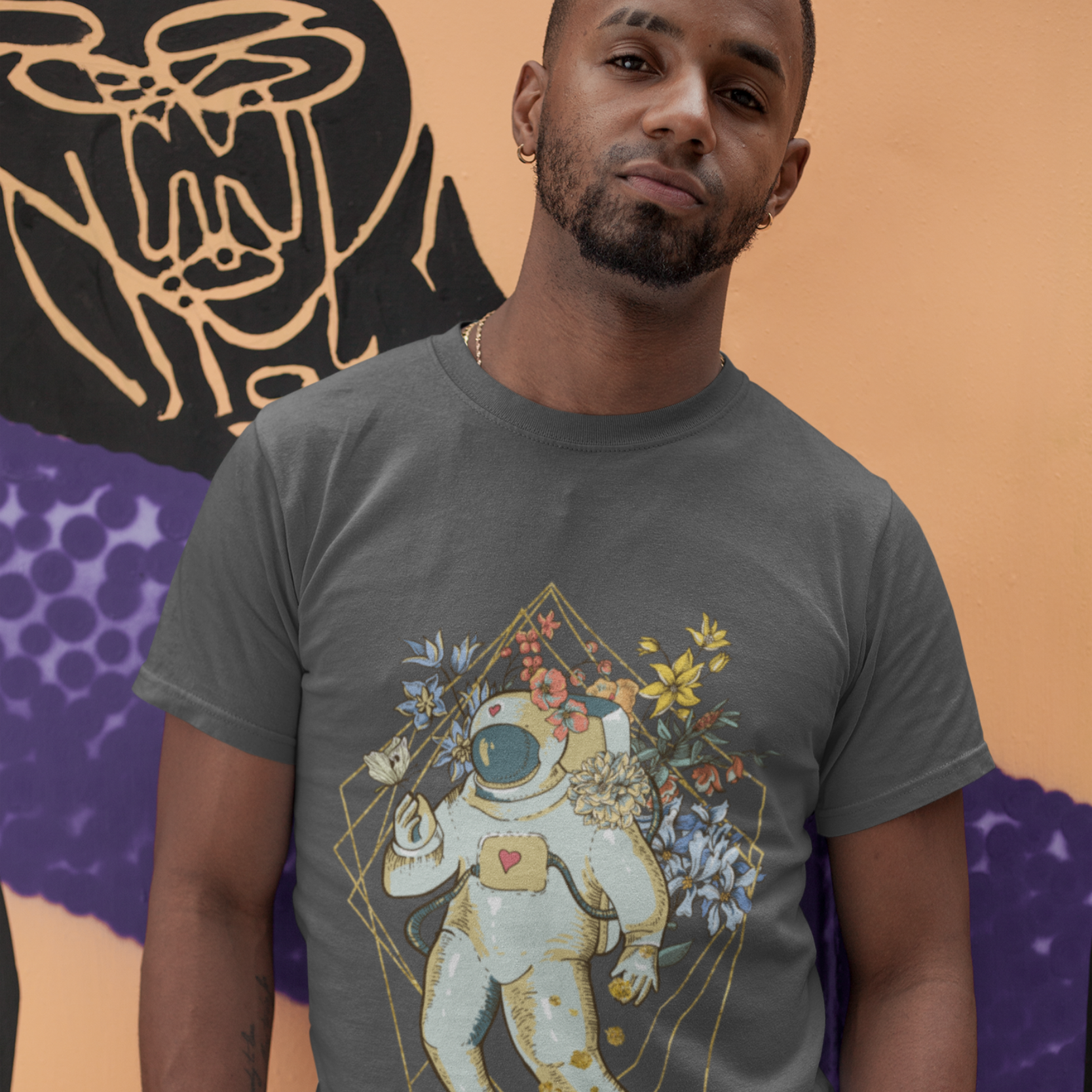 Man wearing a gray t-shirt with an astronaut and floral design against a colorful abstract background