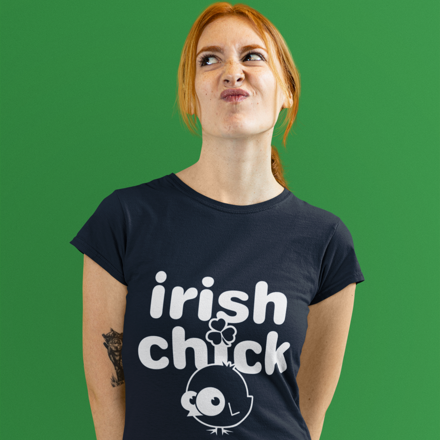 Person wearing a black t-shirt with 'Irish chick' design on a green background