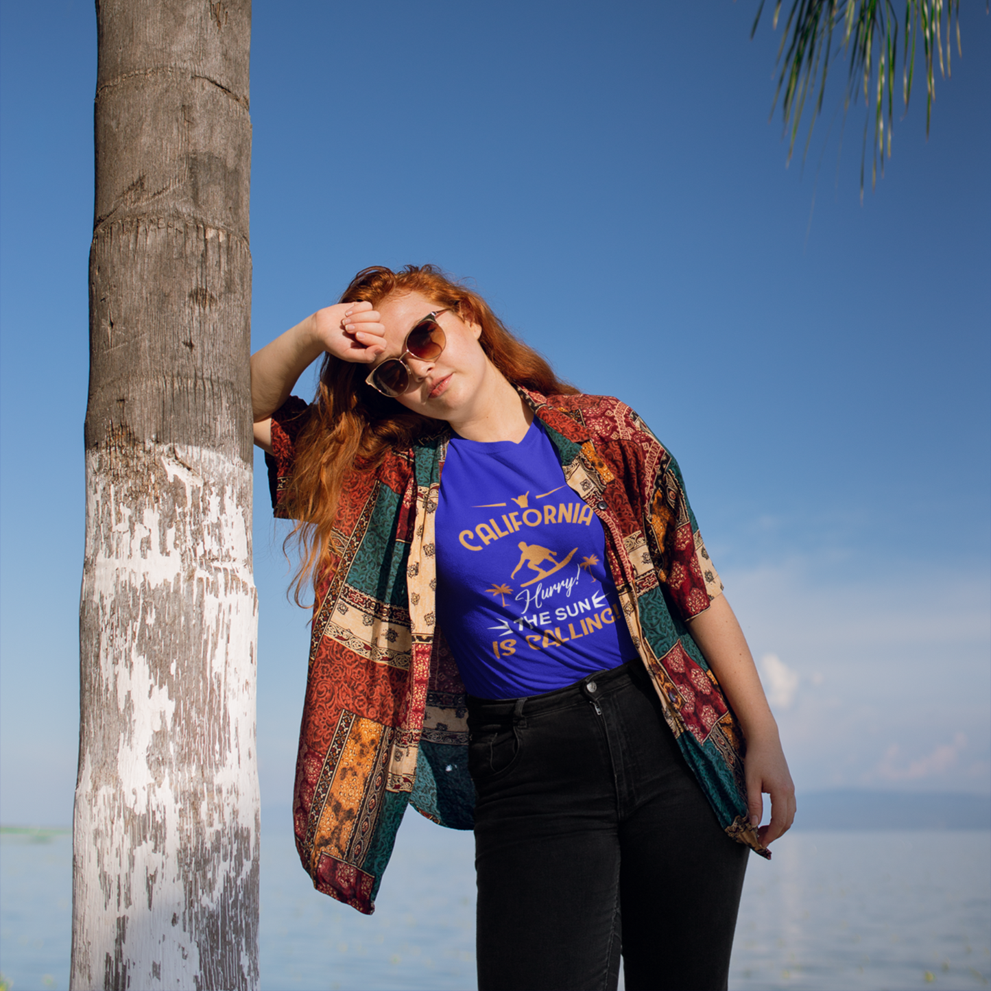 Person standing by a palm tree with a blue sky and ocean background