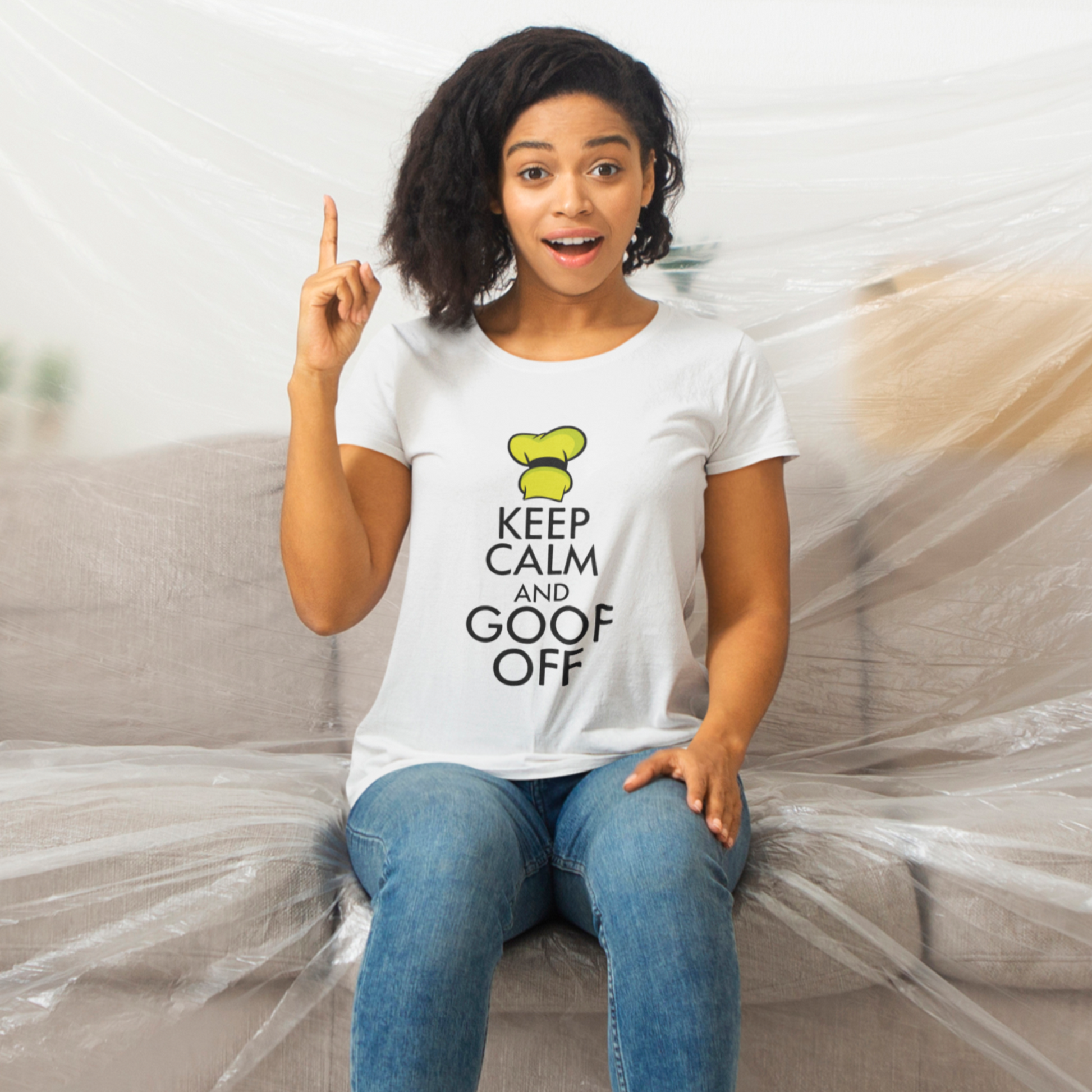 Woman sitting on a couch wearing a white t-shirt with text, surrounded by plastic wrap.