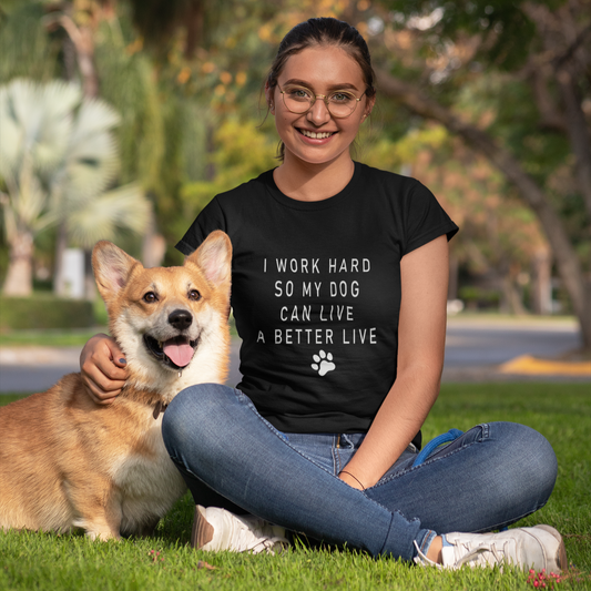 Woman sitting on grass with a dog, wearing a black t-shirt with text.