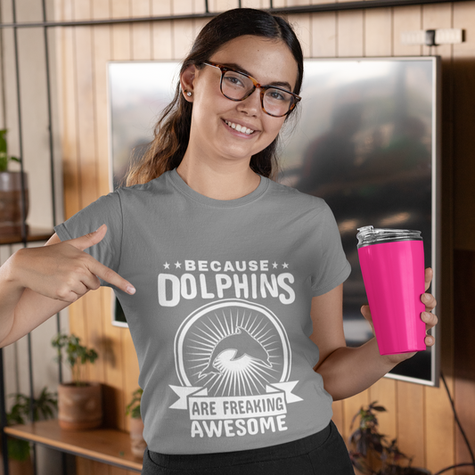Woman wearing a t-shirt with a dolphin design and text, holding a pink cup indoors.